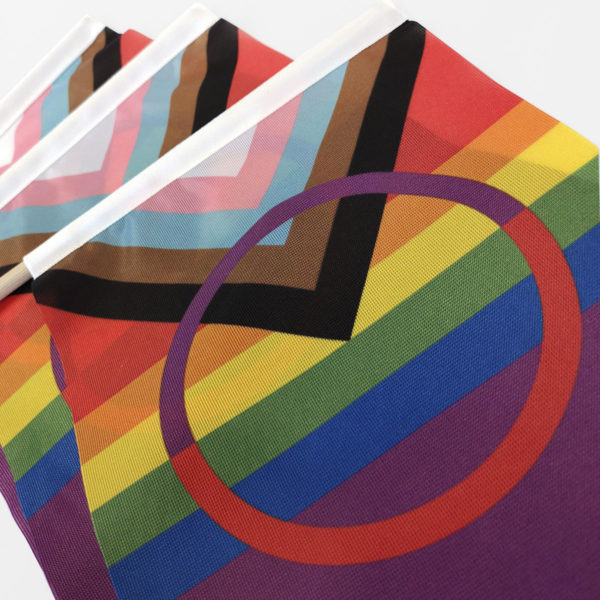 Kirkasvärinen Pride versio saamenlipusta. Kolme sateenkaarenväristä lipua lähikuvassa