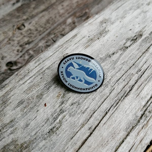 Pieni metallinen pinssi, jossa on Kevon luonnonpuiston logo. Logossa on naalin kuva