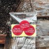 Kuva muovipaketista, jossa 10 kappaletta punaisia pyöreitä tarroja, joissa hyvän joulun toivotukset pohjois-, inarin- ja koltansaameksi