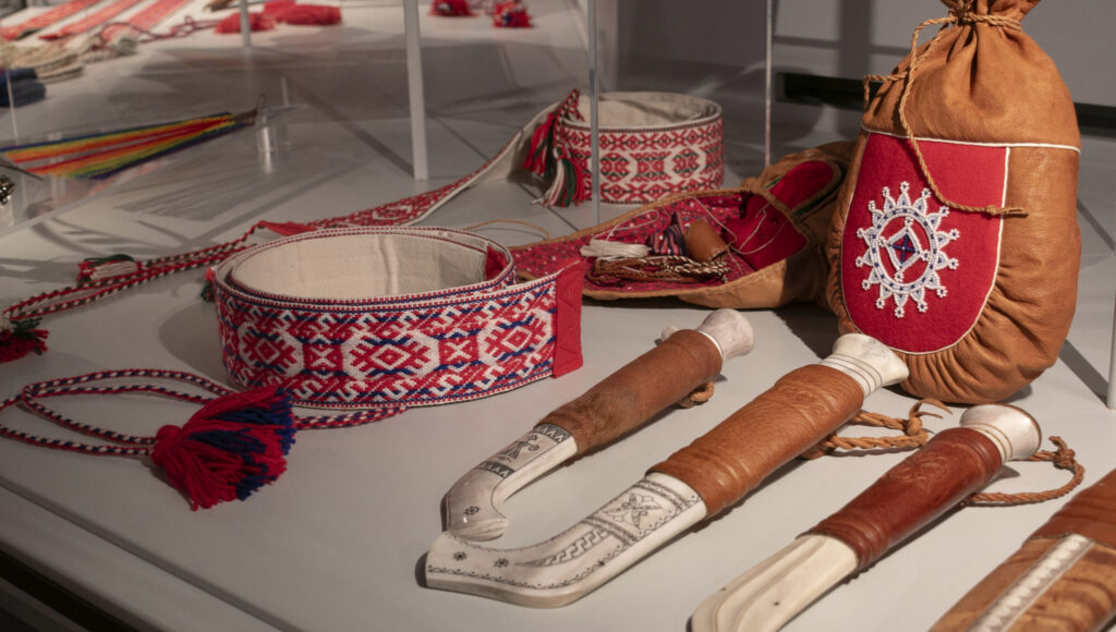 Saamelaisia käsitöitä Saamelaismuseo Siidan päänäyttelyn vitriinissä. Muun muassa, puukkoja, niisivyö ja helmikirjailtu sisnapussi