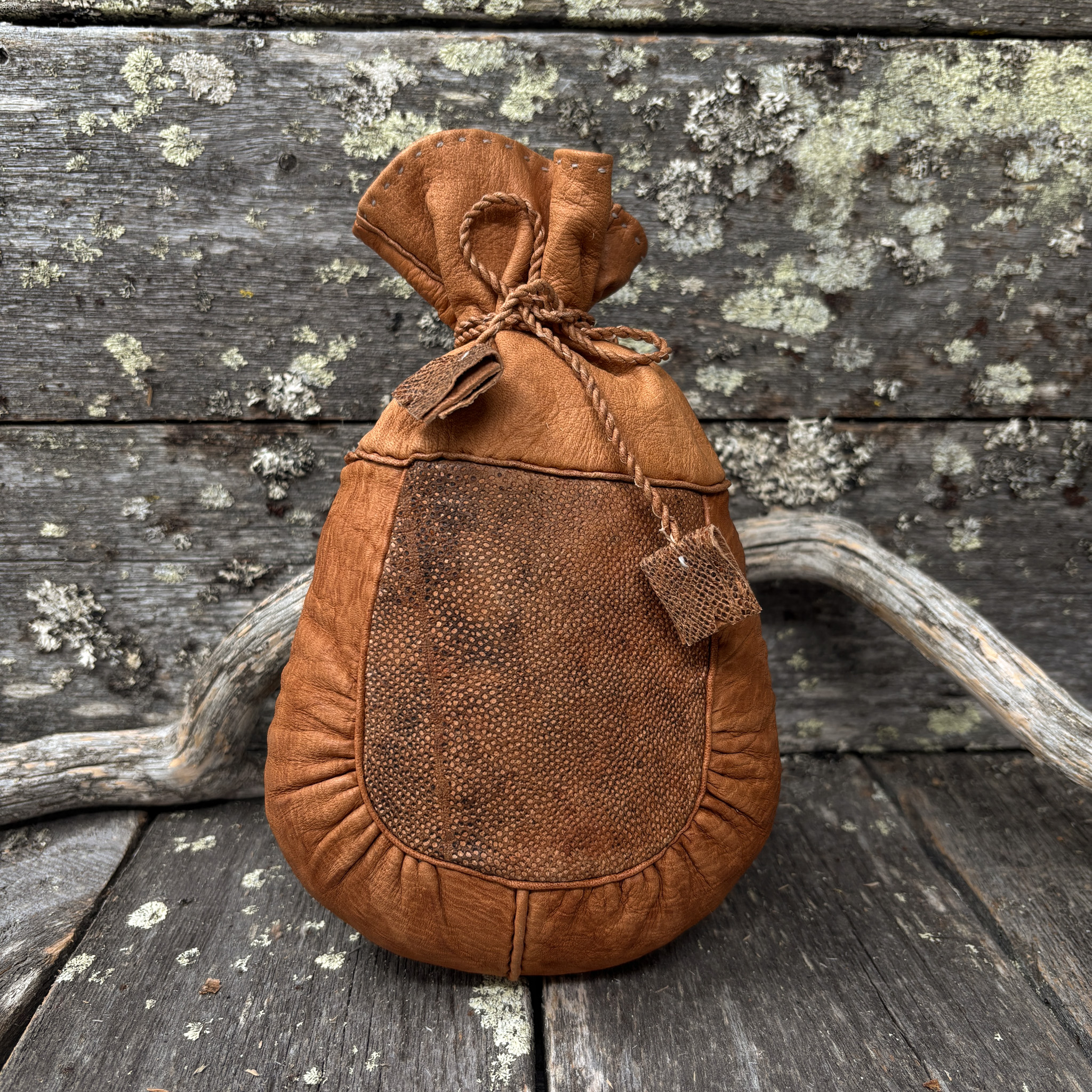 Käsintehty poronnahkainen kahvipussi, jossa parkittua kalannahkaa. Pussin suussa poronnahkaiset nyörit.