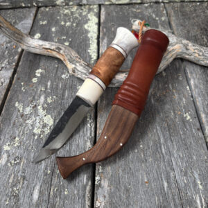 Käsintehty puukko, jossa hiiliterästerä, poronsarvikahva sekä poronsarvesta, koivunpahkasta ja naudannahasta valmistettu tuppi.